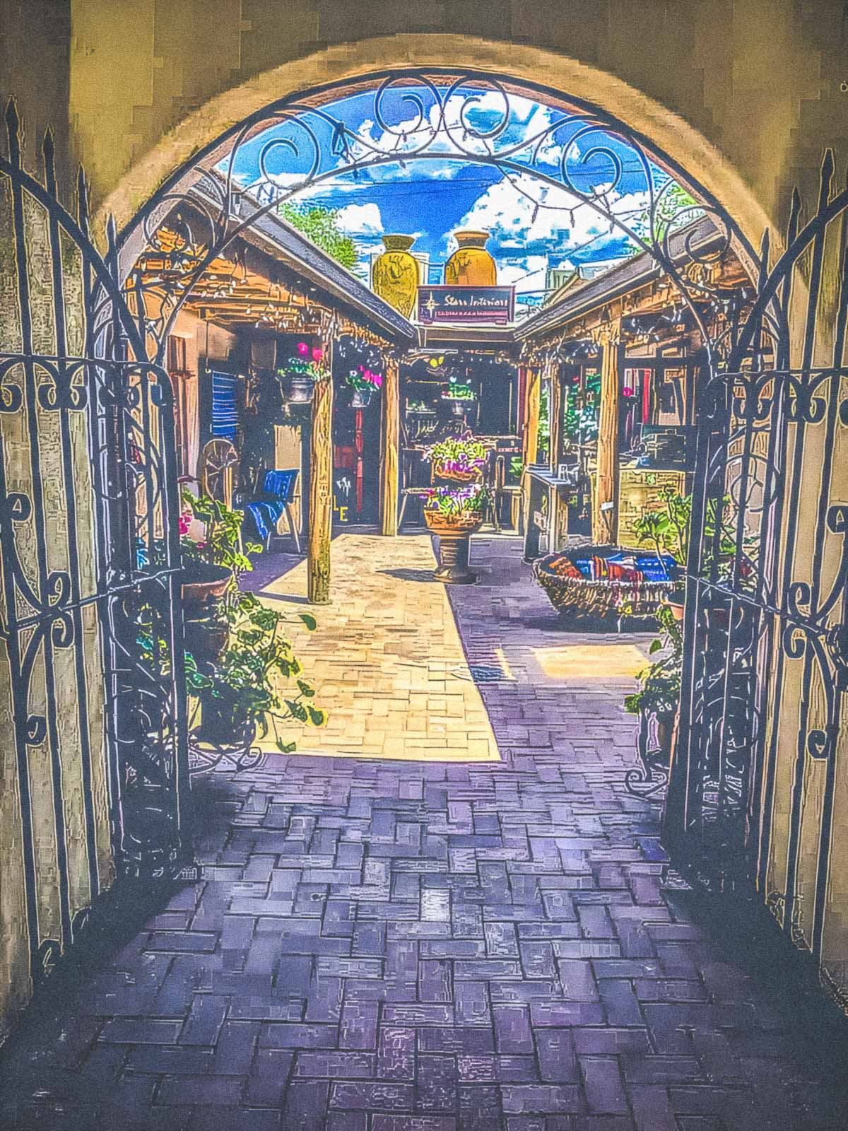 Decorative archway leading to a courtyard in Taos, New Mexico with shops and plants