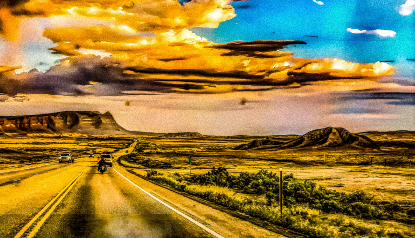 Desert landscape with a road and vehicles under a dramatic sky.