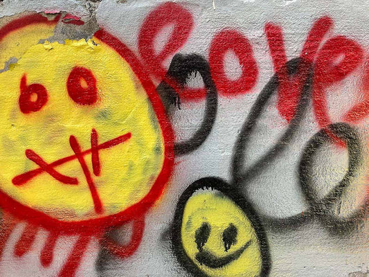 Graffiti with smiley faces and the word 'love' on a textured surface.