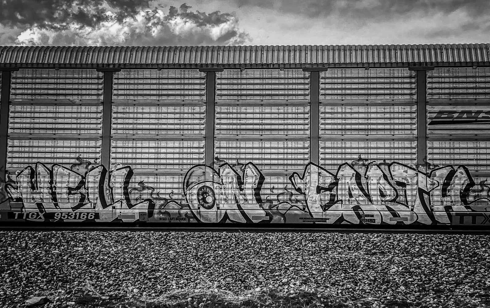 Graffiti on a train car with a cloudy sky in the background