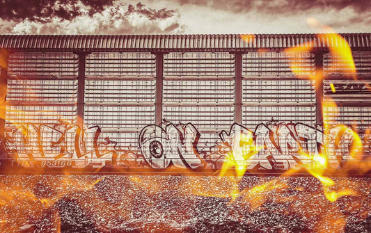 Graffiti on a metal train car with flames and a fiery sky.