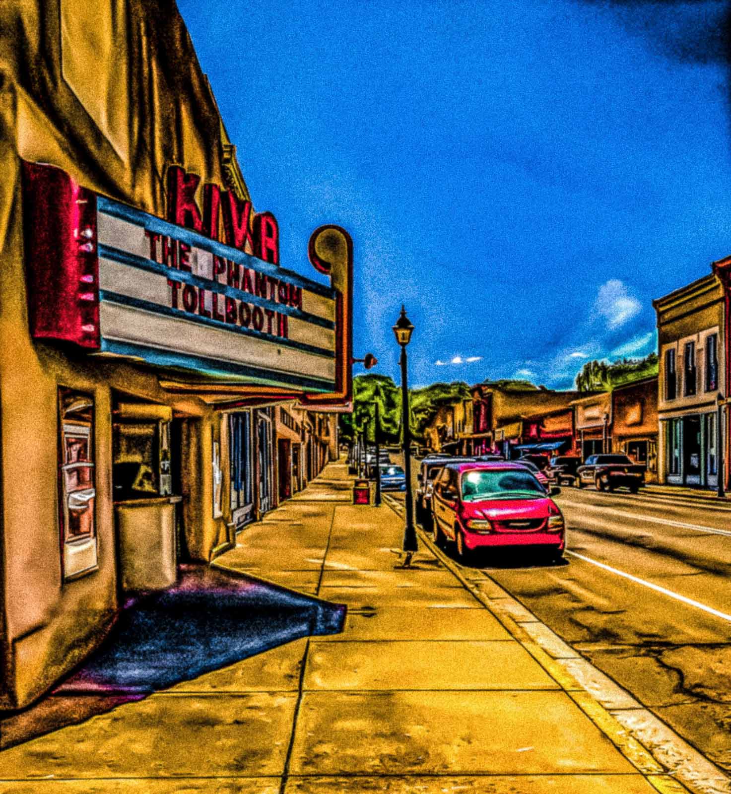 Small town street with the second oldest movie theater in New Mexico; marquee displaying 'The Phantom Tollbooth'.