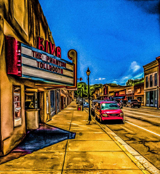 Small town street with the second oldest movie theater in New Mexico; marquee displaying 'The Phantom Tollbooth'.